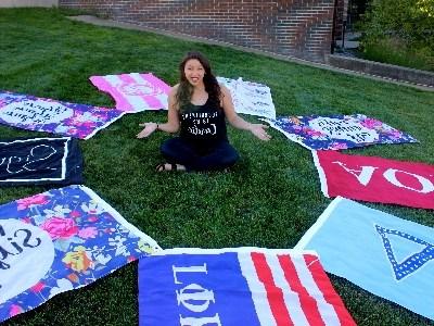 Jordan Sheatzley sits surrounded by Greek Life flags