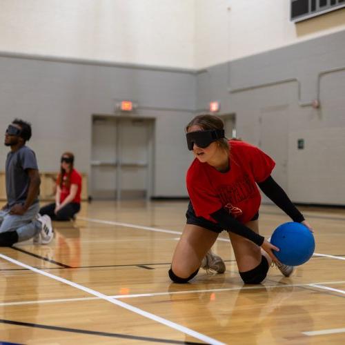 Student participating in goalball at an adaptive intramural sports event.