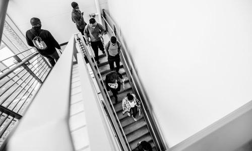 Students walk down a staircase. Photo is taken from above