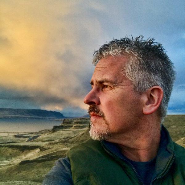 portrait of John Noltner, in background is scenic view of lake, cliffs