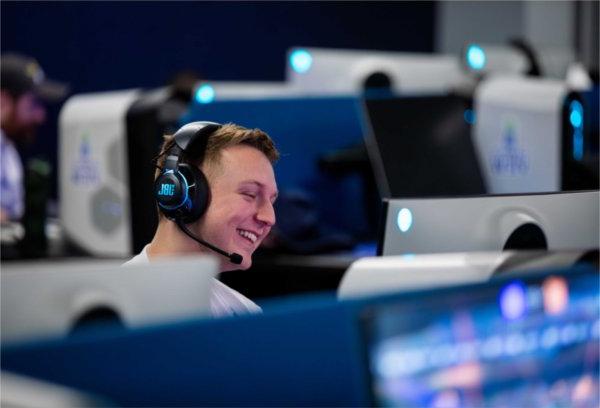 A student smiles while wearing a headset as they game in an esports tournament.  