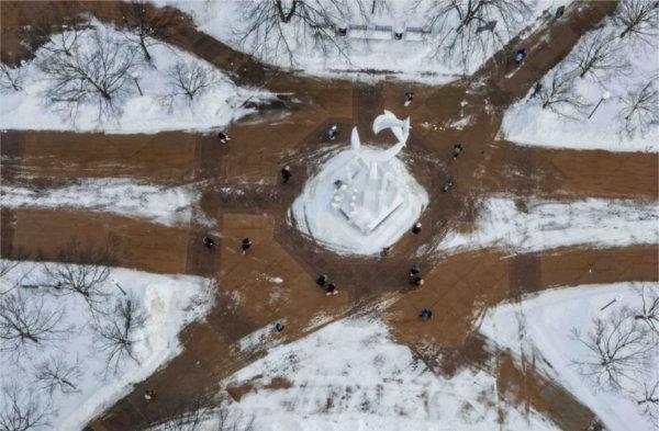  As seen from a drone, students walk past a white sculpture on intersecting paths. 