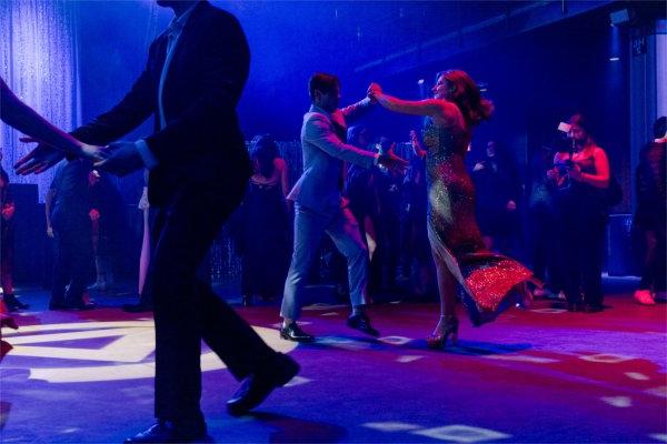 A couple shows off their impressive moves on the dance floor with blue lights filling the room. 