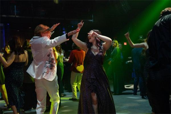 A couple enjoys the music while on the dance floor with a beam of green light highlighting their moves. 