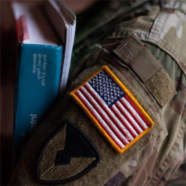 A person with an American flag on their sleeve holds books.