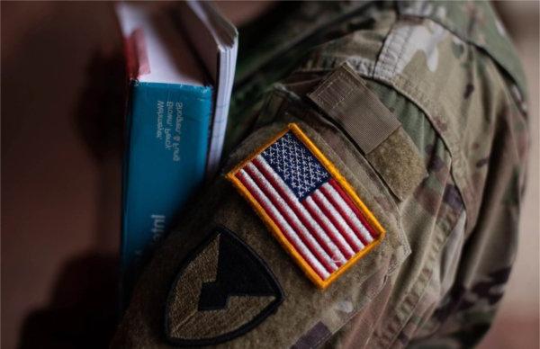 A person with an American flag on their sleeve holds books.