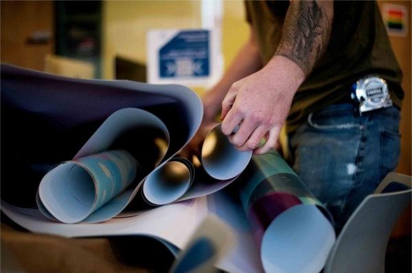 An installation worker unravels a piece of the vinyl mural and preps it to go on the wall. 