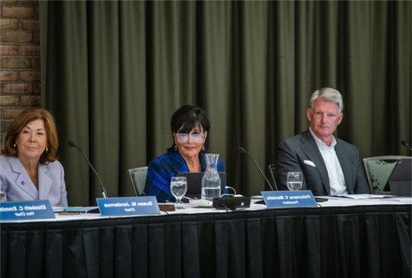 Three people sit at a table during a meeting.