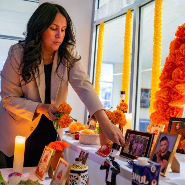 Thalia Guerra-Flores places flowers at the Día de Muertos (Day of the Dead) altar in the Office of Multicultural Affairs.