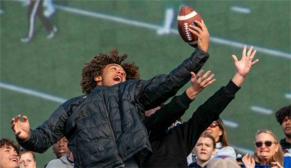  A football fan reaches out in an attempt to catch a football kicked into the crowd.