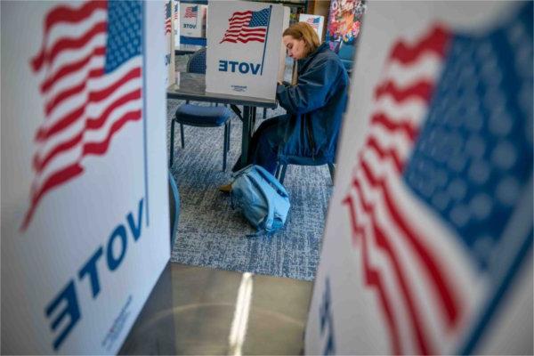  A student votes near pictures of American flags.