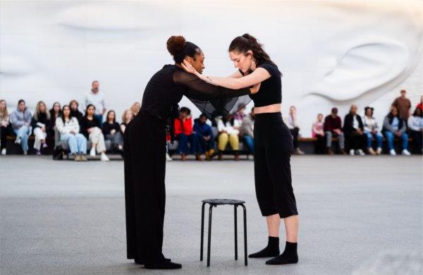  Two dance and theatre students wrap their arms around each other in a performance.