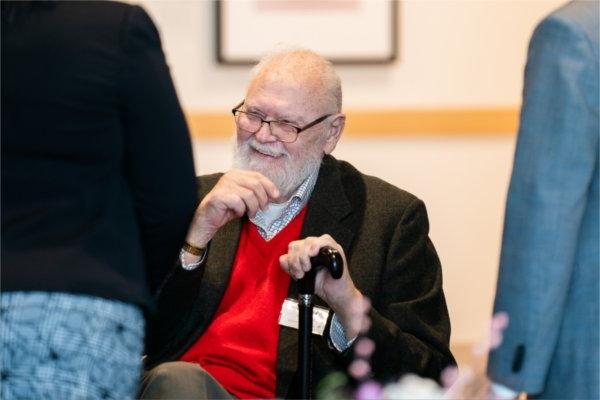 Vernon Ohlman seated in chair, hand on cane, laughing