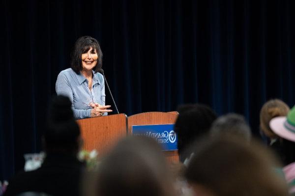 President Philomena V. Mantella at the podium in a light blue jacket 