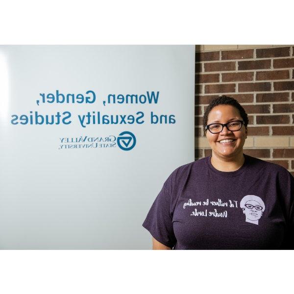 Ayana Weekley standing beside sign that reads Women, Gender, and Sexuality Studies with GVSU wordmark underneath