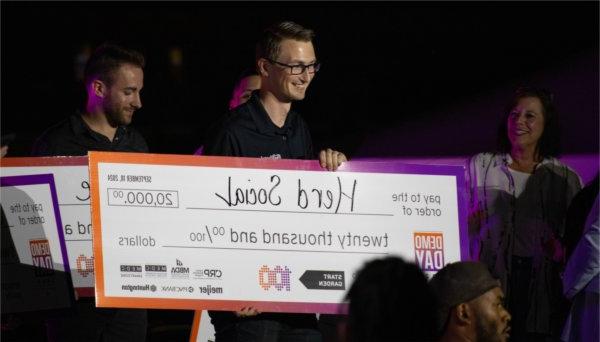 Zachary DeBruine, assistant professor of computing, poses for a photo with a large check after his Herd Social project was selected as one of the top 10 projects at Start Garden's Demo Day. 