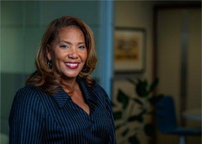 LuWanna Williams wears a navy blue pinstriped blazer and smiles.