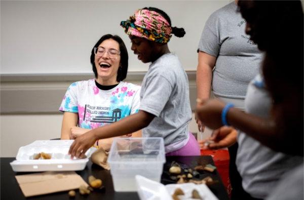 Frederik Meijer Honors College student Sofia Magan, right, laughs with Kentwood's Endeavor Elementary School students while they were looking at rocks and fossils. The students were part of a multicultural leadership team that visited the Allendale Campus May 1. Magan is a sophomore studying biomedical sciences.