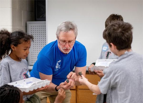 Peter Wampler, professor of geology, center, identifies rocks for Endeavor Elementary School students as they participate in geology stations at the Padnos Hall of Science. The students were part of a multicultural leadership team that visited the Allendale Campus May 1.