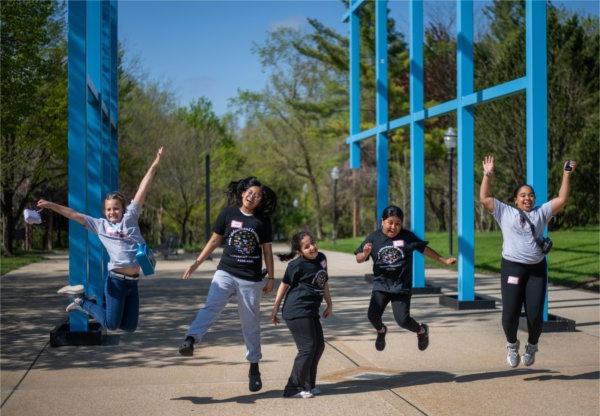 Endeavor Elementary School students jump in the air in front of the Transformational Link.