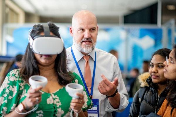 Scott Truskowski, center, presents on using VR modules to augment student learning of lab skills during the 2024 Reach Higher Showcase.