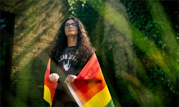  A person drapes themselves in a pride flag for a portrait.