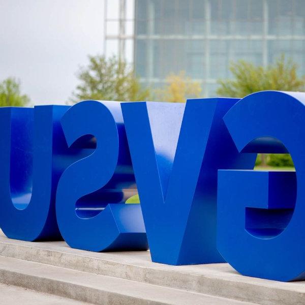 Large blue letters on a small cement pedestal spell out GVSU.