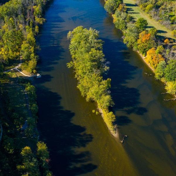 A river with a small island in the middle is seen from above.