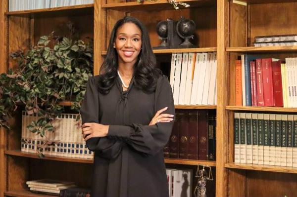 Krya Harris Bolden stand with arms crossed in front of a bookcase