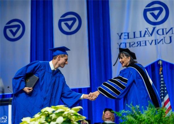 President Mantella shakes a student's hand as they walk across the stage at Commencement.