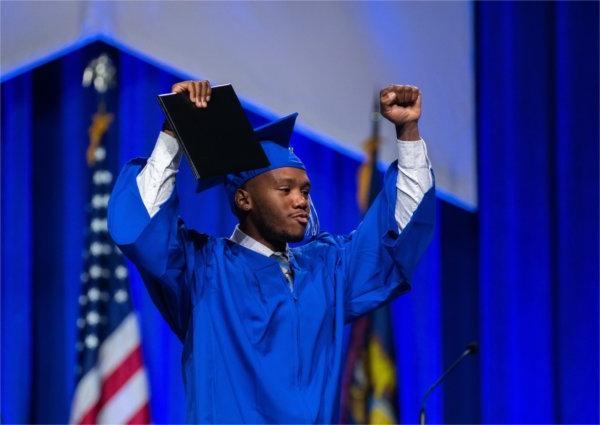 A student walks across the stage during Commencement.