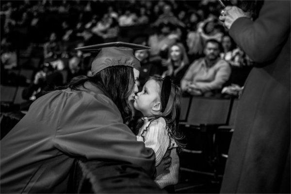 A graduate kisses a child after commencement.