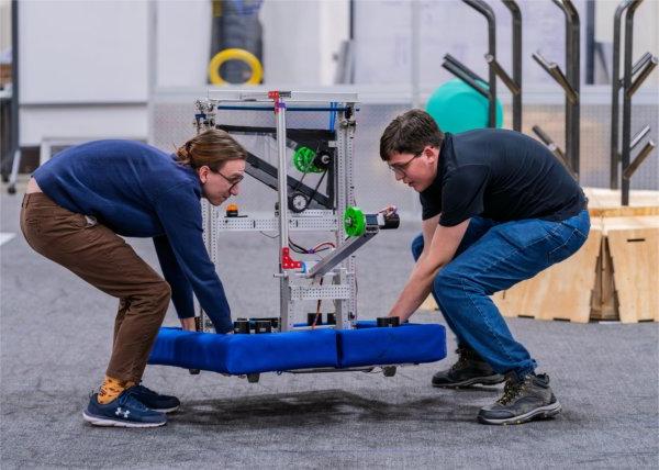 Darren Fife, left, and Quentin Brook carry in a robot