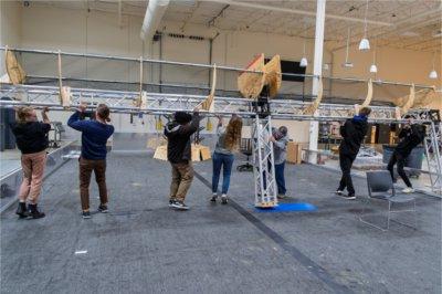 row of people lifting caged net onto structure