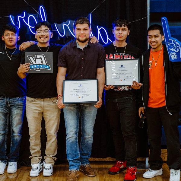 five students stand in front of neon Laker for a Lifetime, holding certificates or other props