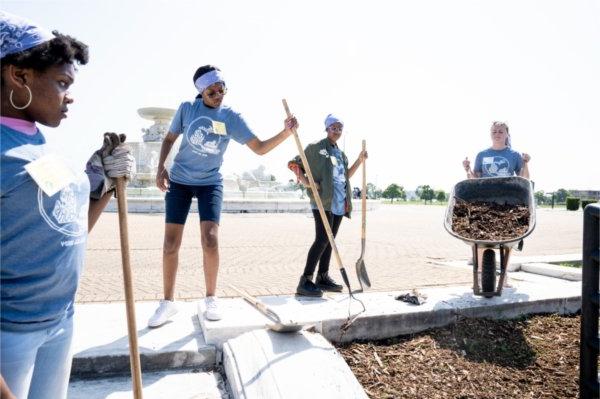 Volunteers and students spread wood chips around landscaping around the James Scott Memorial Fountain at Belle Isle Park in Detroit.