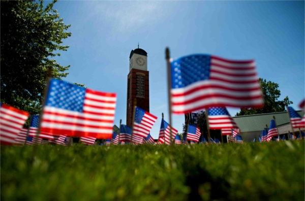  Small American flags frame a carillon tower on a college campus. 