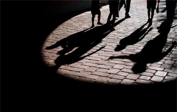  Shadows of children and parents make shapes on a brick walkway.