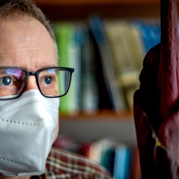 Todd Carlson, wearing a mask, looks at the blooming voodoo lily.