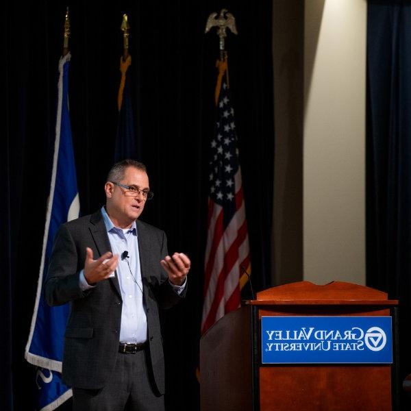 David Leich, executive director of global supply chain for General Motors, speaks next to a podium and in front of several flags on a stage.