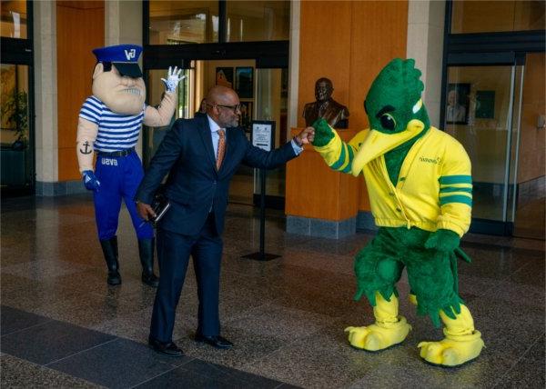 VP Truss gives a fist bump to a mascot, Louie the Laker in the background