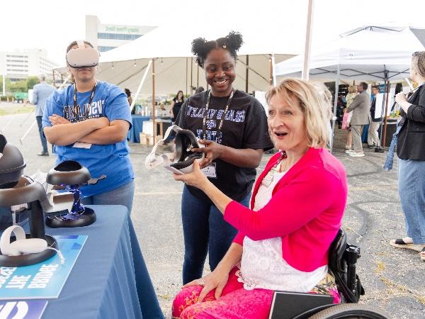 Jocelyn Dettloff, major gifts director for Mary Free Bed, hands a VR headset back to GVSU student Ruth Yeboah after watching a virtual tour of the future Joan Secchia Children's Rehabilitation Hospital.