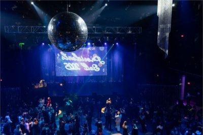 An above shot of a room full of Lakers dancing. A sign hanging reads Presidents&rsquo; Ball 2025. A large silver disco ball hangs from the ceiling.