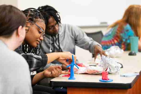  College students work together on a project in a classroom setting. 