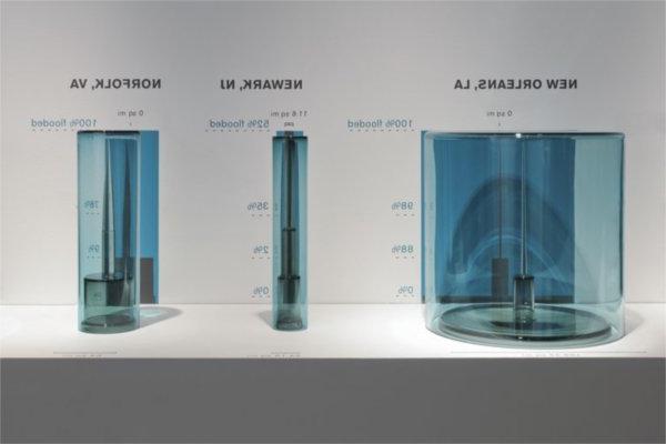 glasswork, three vessels with city names to depict the level of flooding