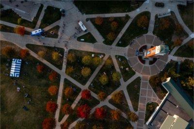 A carillon tower and zigzag patterns of sidewalks of a college campus are seen from a drone.