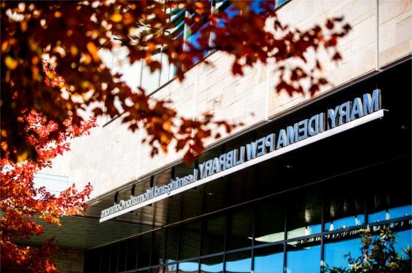  Red maple leaves frame the sign for the Mary Idema Pew Library learning and information commons.  