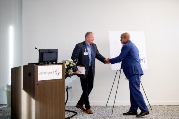 two people shake hands next to a podium