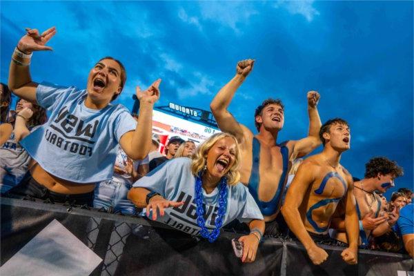 College football fans scream and cheer during a football game. 