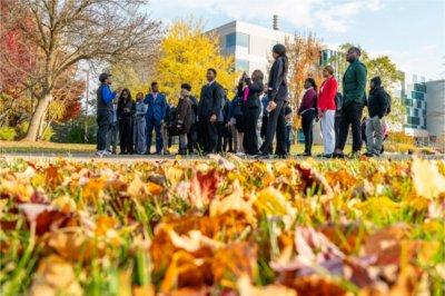 student leading tour near Zumberge Hall, ground covered in fall leaves